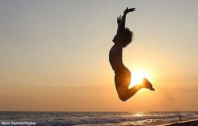 Junge springt hoch vor Sonnenuntergang am Meer